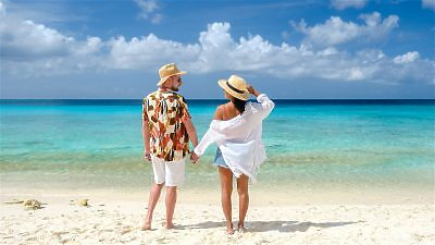 Man and woman holding hands standing on a sandy beach